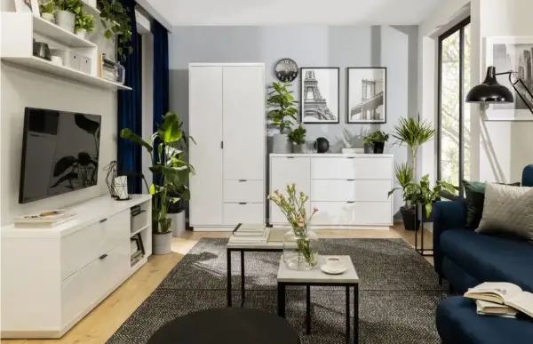 Nowoczesny salon z białymi meblami, granatową kanapą i mnóstwem zieleni. Inspiracja, jak ustawić kwiaty w salonie, by stworzyć przytulną atmosferę.